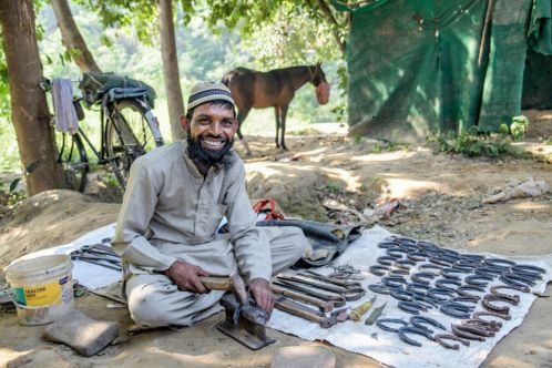Man sitting on floor smiling as he makes horse shoes